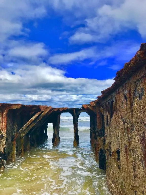 Rusted pier structure framing turquoise ocean waters and blue sky