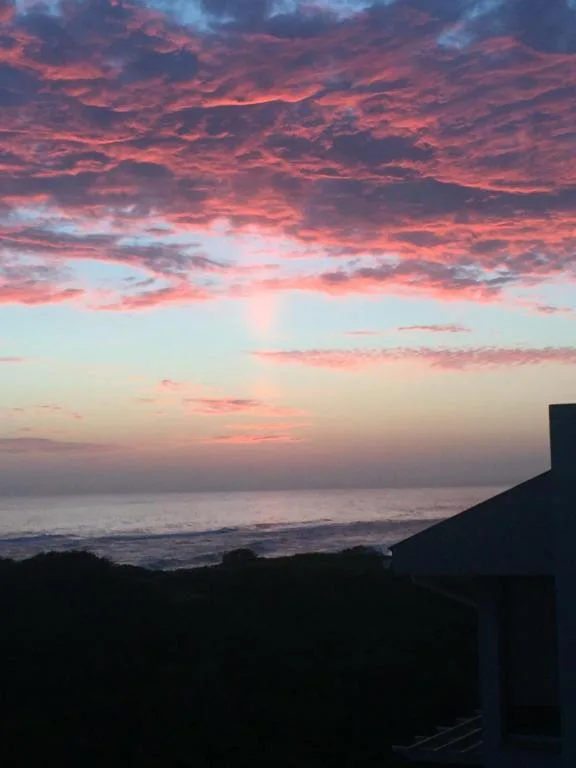 Stunning sunset over the ocean with dramatic pink and red clouds