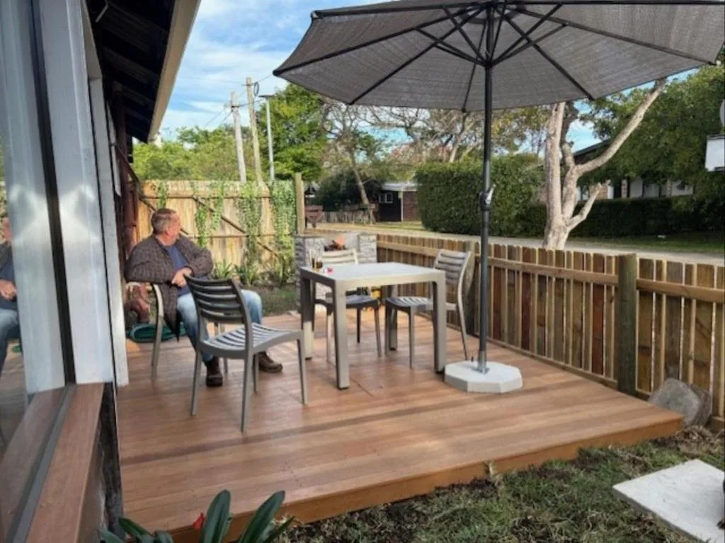 Wooden deck with outdoor seating, umbrella, and garden views