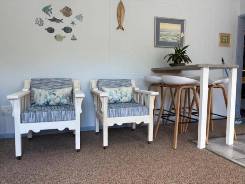 Coastal-themed lounge with white armchairs and high bar seating area