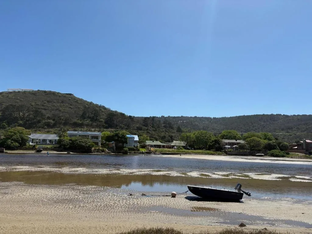 Scenic lagoon and beach view with forested hills and riverside cottages
