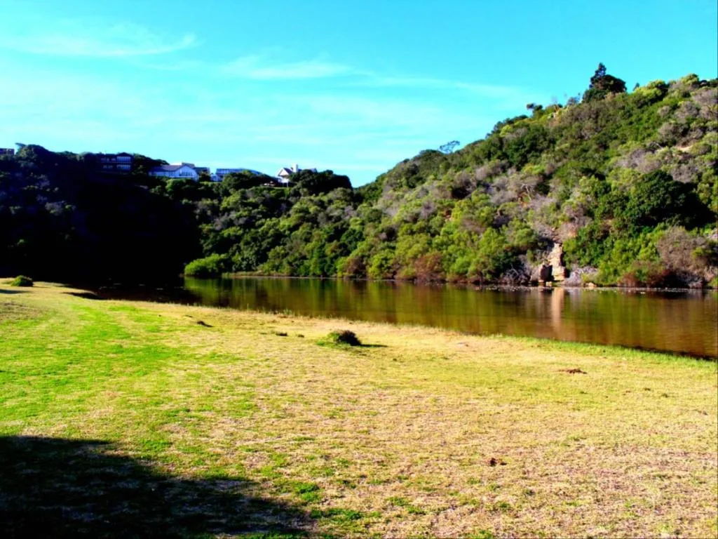 Scenic river and forested hillside view from grassy property grounds