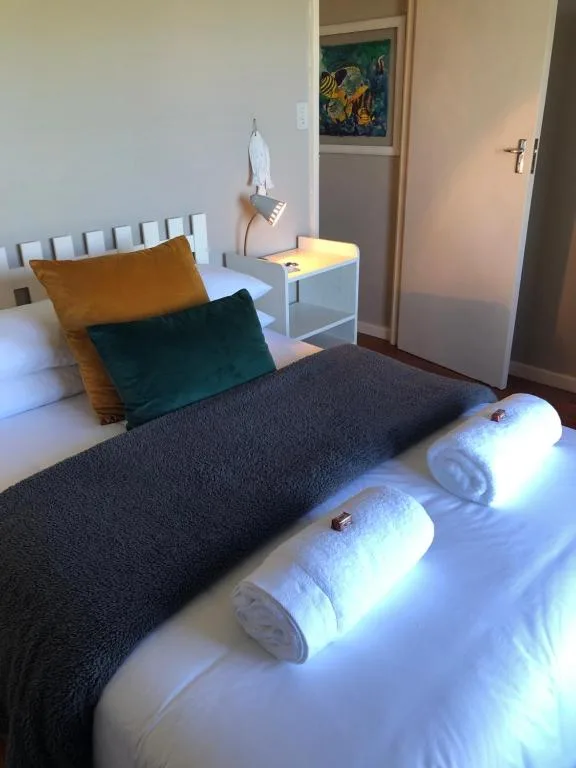 Bright bedroom with bed, colorful pillows, and rolled towels