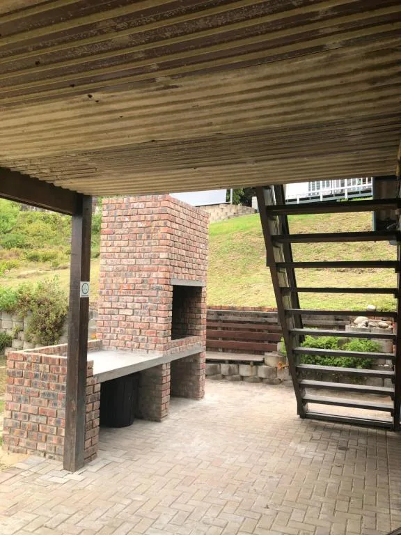 Covered outdoor braai area with brick fireplace and wooden gates