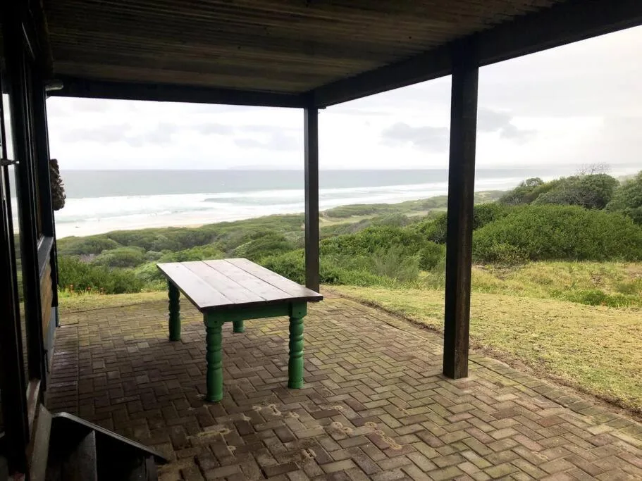 Covered patio with table overlooking coastal lagoon and lush green landscape