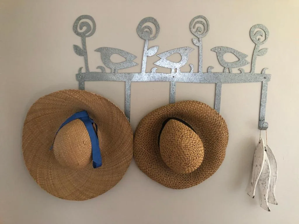 Decorative metal hat rack with straw hats and coastal-themed embellishments