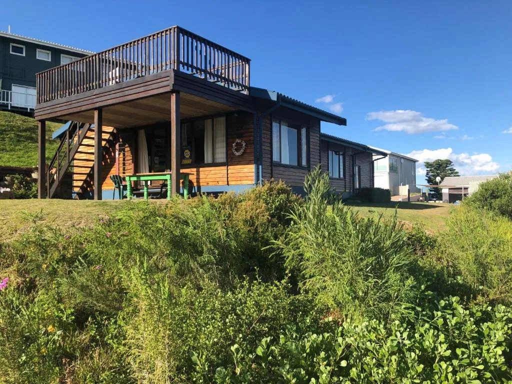 Modern wooden cottage with upper deck and green garden landscape
