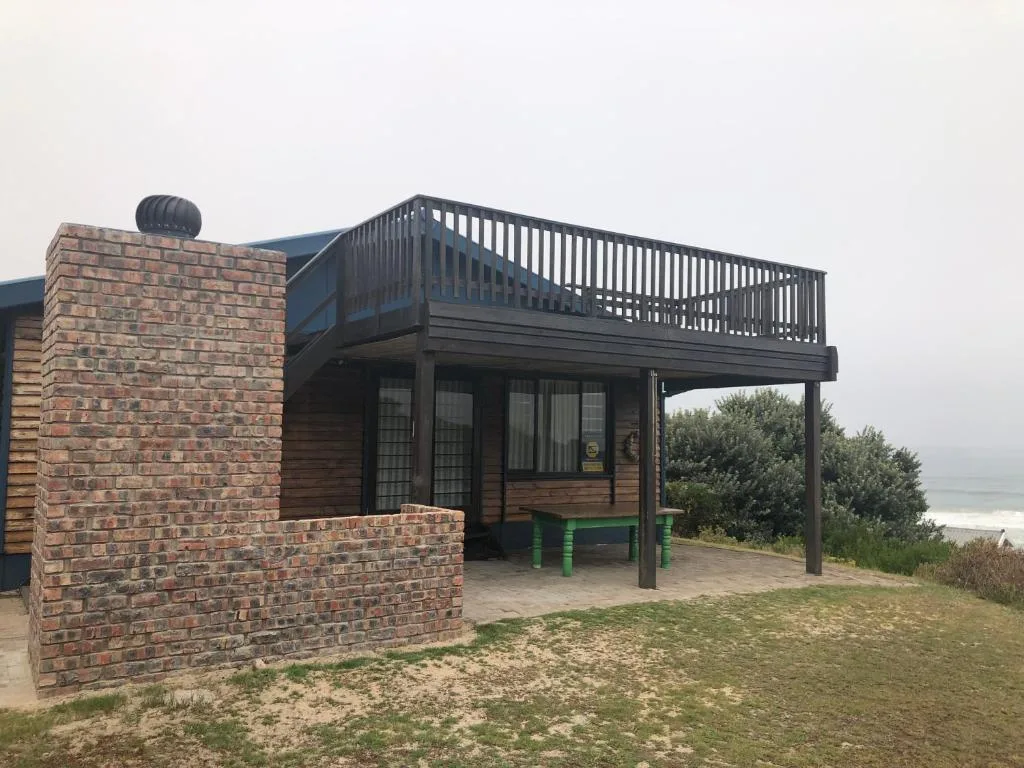 Modern beach cottage with brick chimney and elevated deck overlooking coastal vegetation