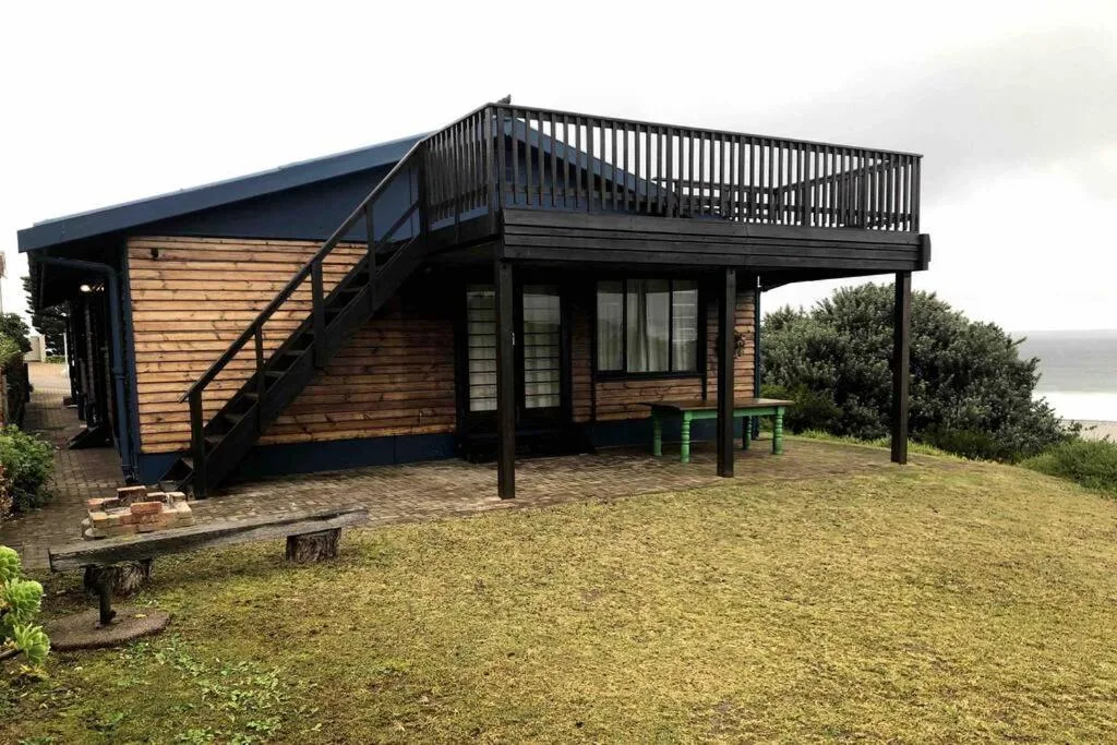 Modern beach cottage with elevated deck, wooden siding, and water views