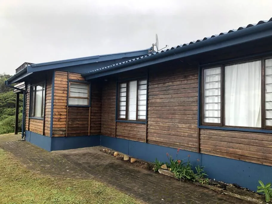 Wooden cottage with blue trim and covered porch entrance