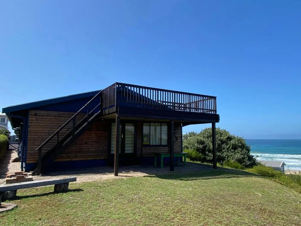 Modern beach cottage with deck overlooking ocean, dark wood siding and stairs