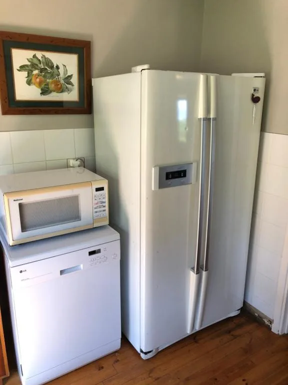 White refrigerator, dishwasher, and microwave in compact kitchen corner