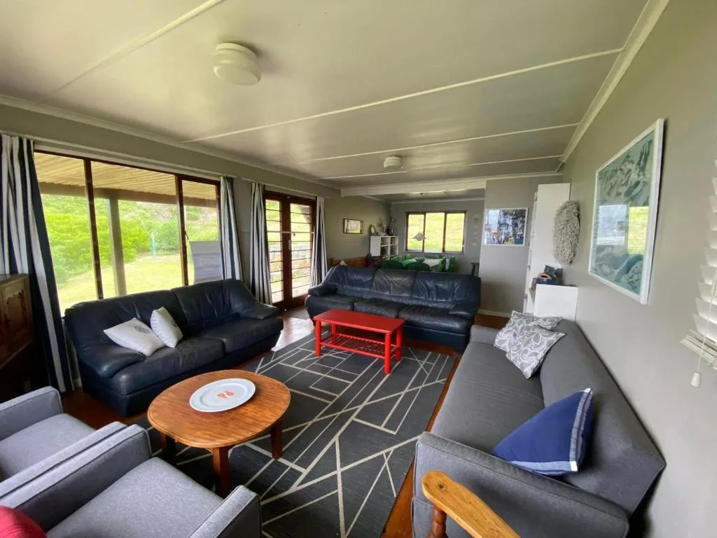 Spacious lounge with black leather sofas, wooden coffee table, and garden views