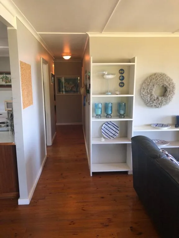 Open-plan lounge with white shelving unit displaying decor and seating area