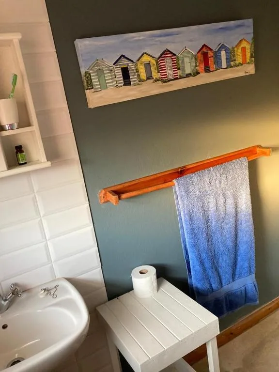 Bathroom with sink, beach hut artwork, and wooden towel rack