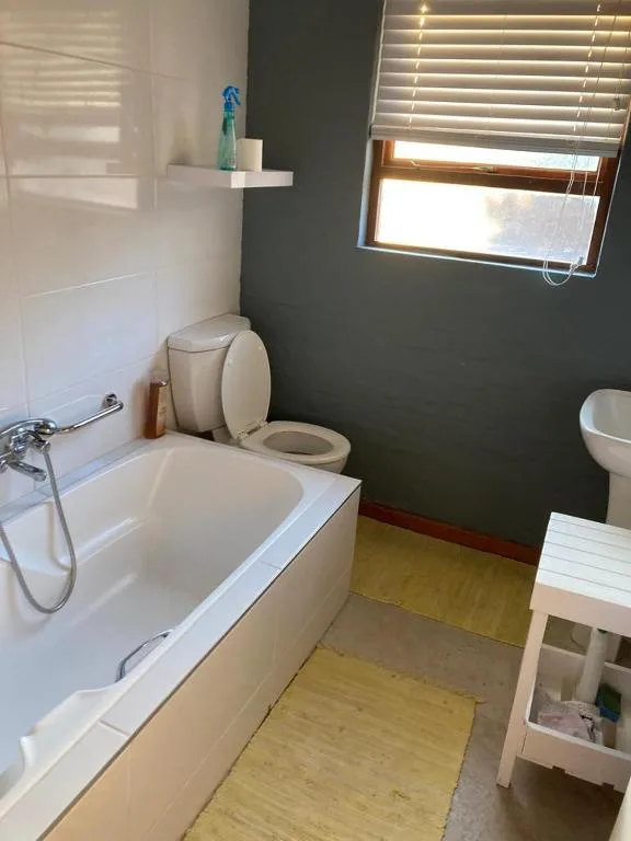 Modern bathroom with bathtub, toilet, and natural light from window