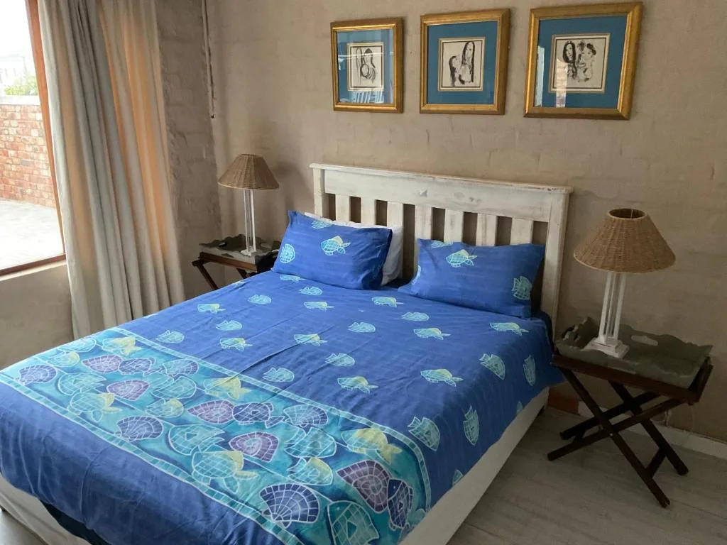 Bright bedroom with blue turtle-patterned bedding and white wooden headboard
