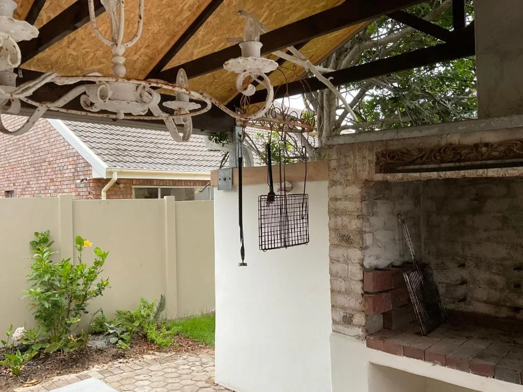 Covered patio with decorative chandelier, braai area, and garden views