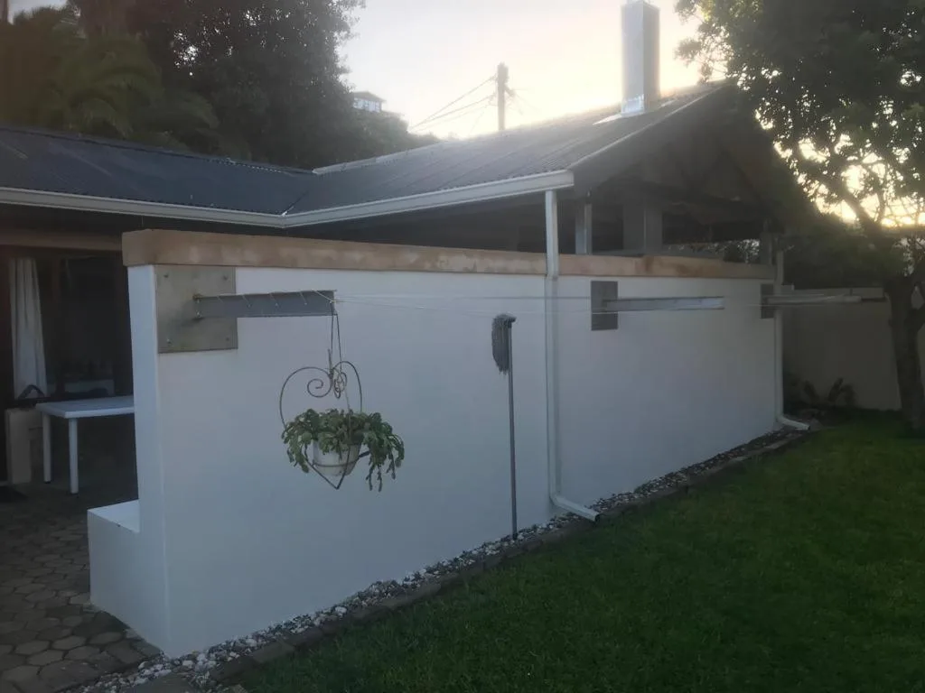 White-walled cottage with blue roof and hanging basket planter at dusk