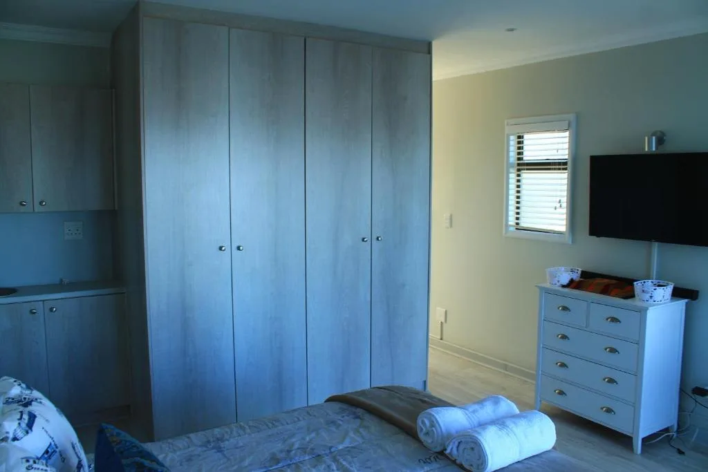 Bright bedroom with large blue wardrobe, dresser, and rolled towels on bed
