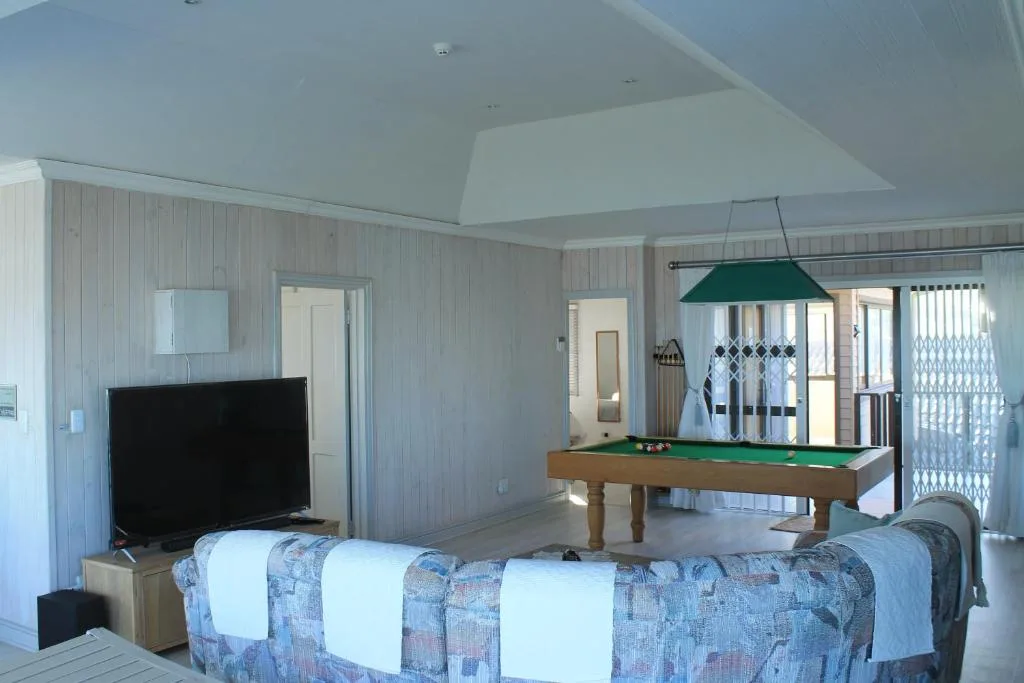 Open lounge with sofa, TV, and pool table in bright space