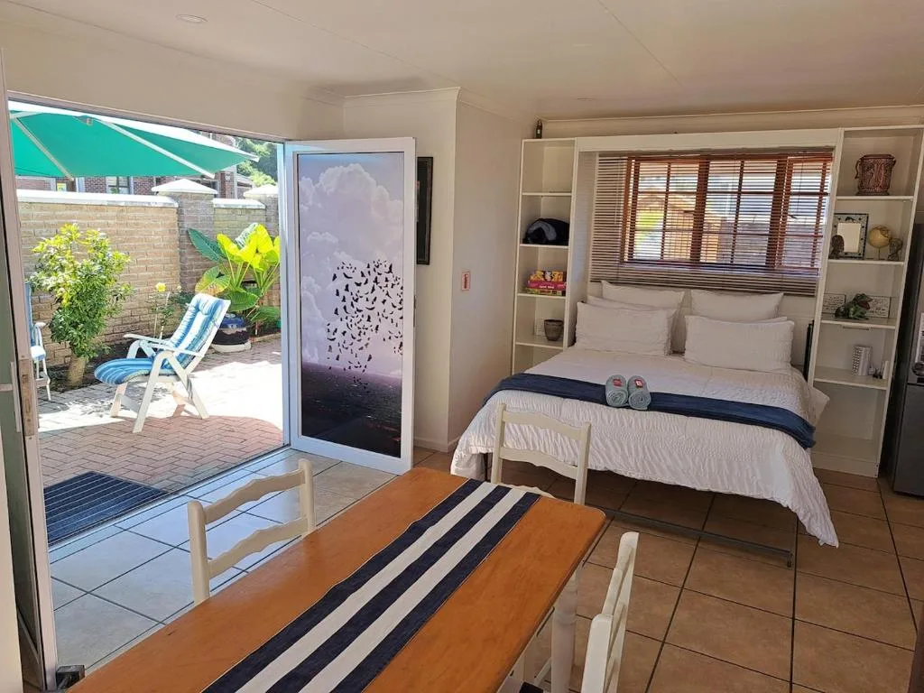Bright bedroom with queen bed, built-in shelving, and patio access outdoors