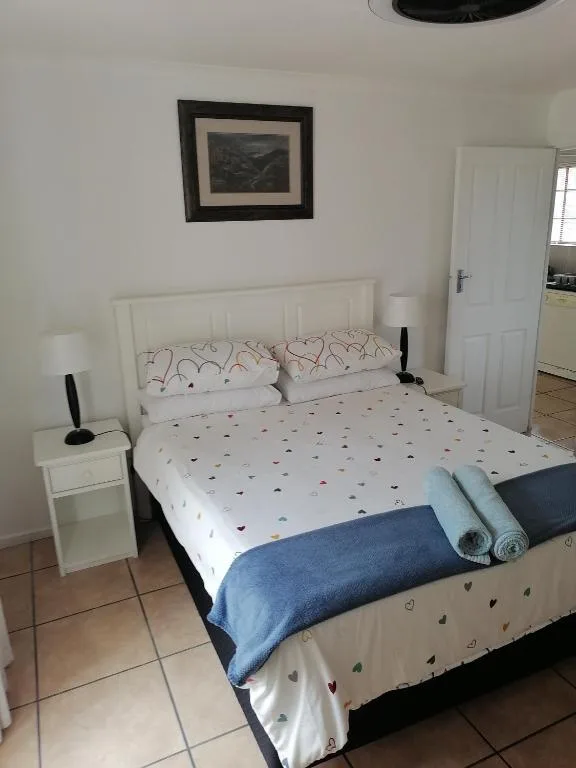 Bright bedroom with white bed frame, patterned bedding, and framed artwork