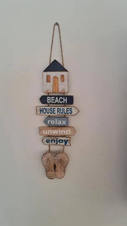 Decorative wooden beach house rules sign hanging on wall