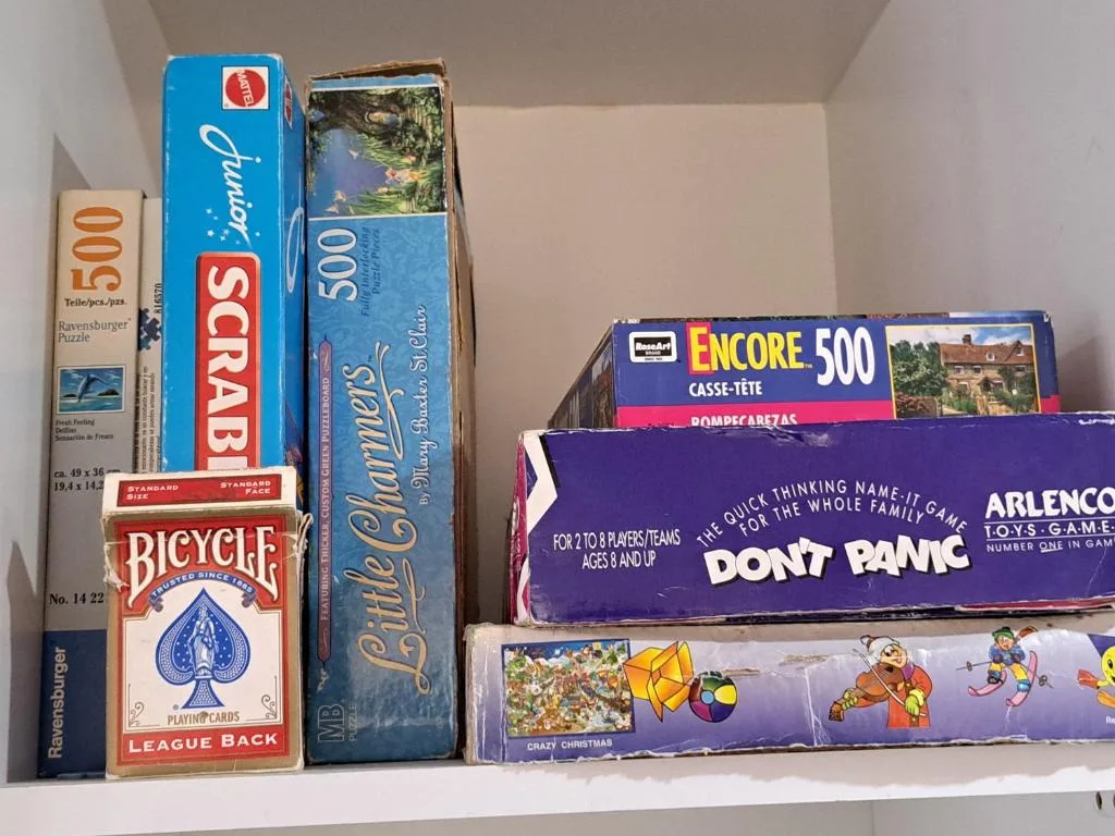 Shelf displaying vintage board games, puzzles, and playing cards