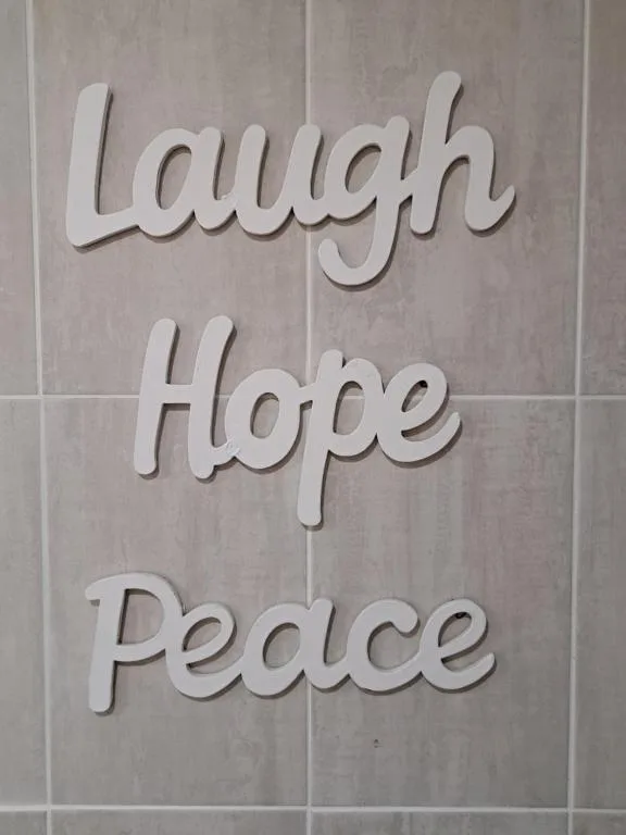 White wall decor displaying inspiring words Laugh Hope Peace