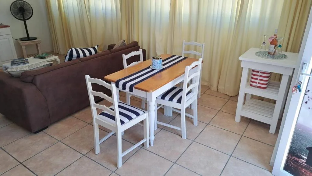Wooden dining table with white chairs and striped cushions in open-plan space