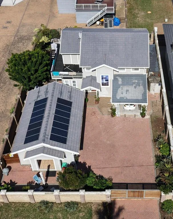 Aerial view of cottage with solar panels and brick driveway