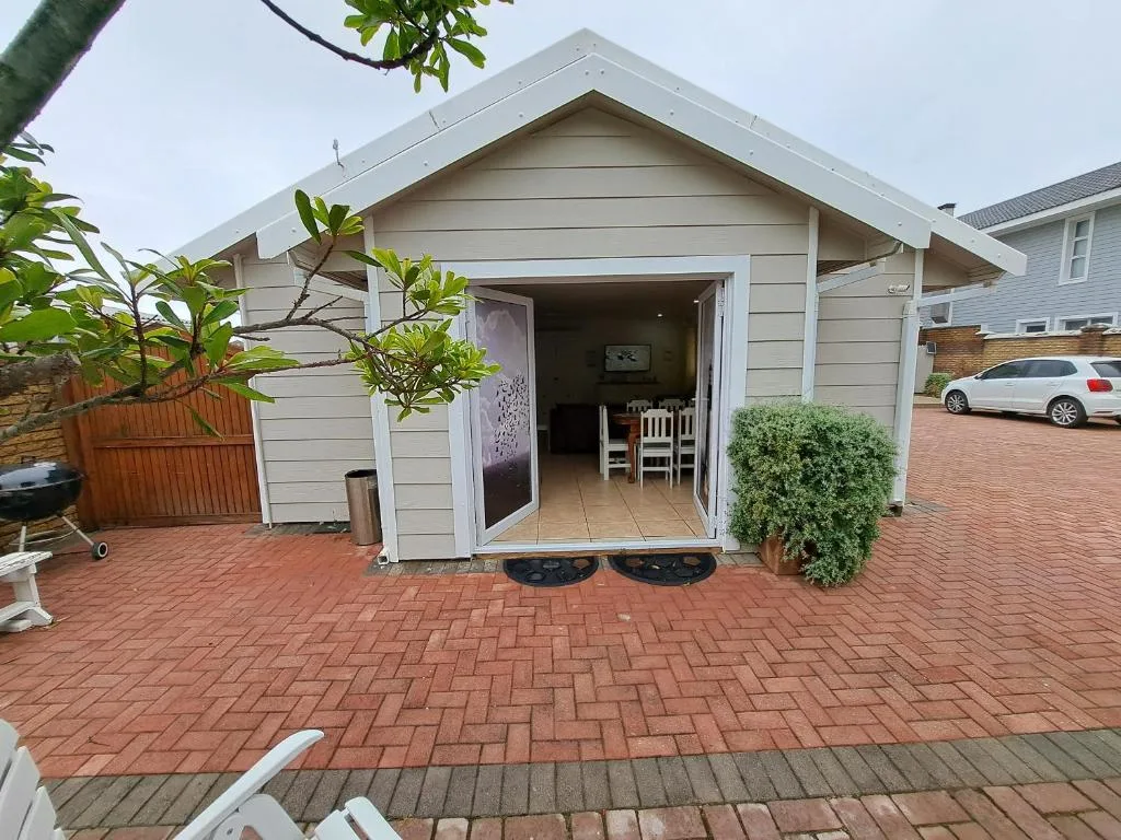 Modern white cottage with open sliding doors and brick paver driveway