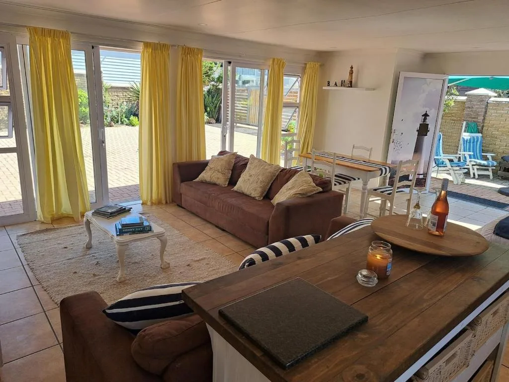Spacious living room with brown sofa, yellow curtains, ocean views through glass doors