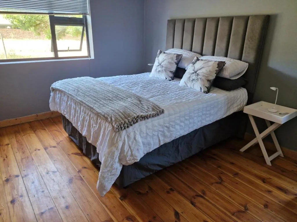 Modern bedroom with upholstered headboard, crisp white bedding, wooden floors