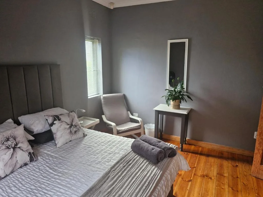 Spacious bedroom with upholstered headboard, comfortable seating, and natural light