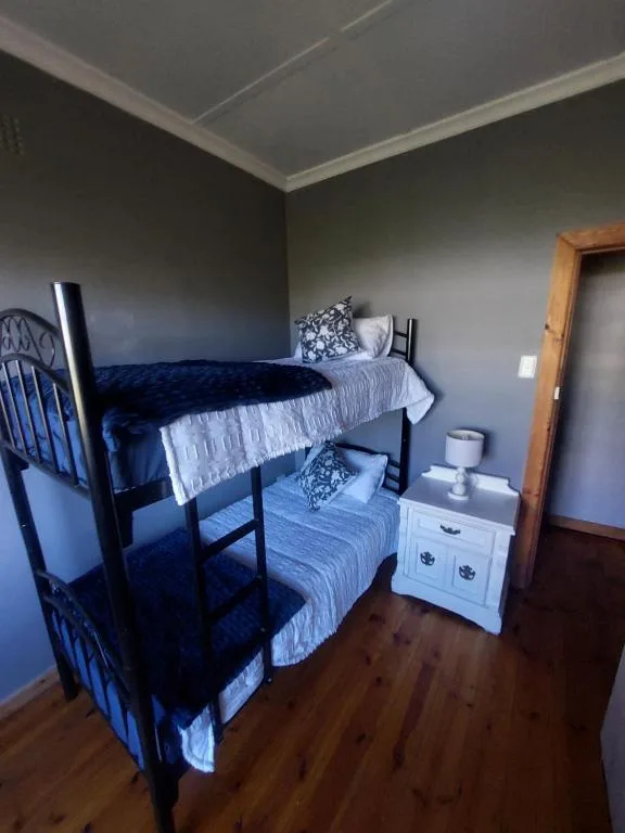 Bedroom with black bunk beds, blue striped bedding, white nightstand