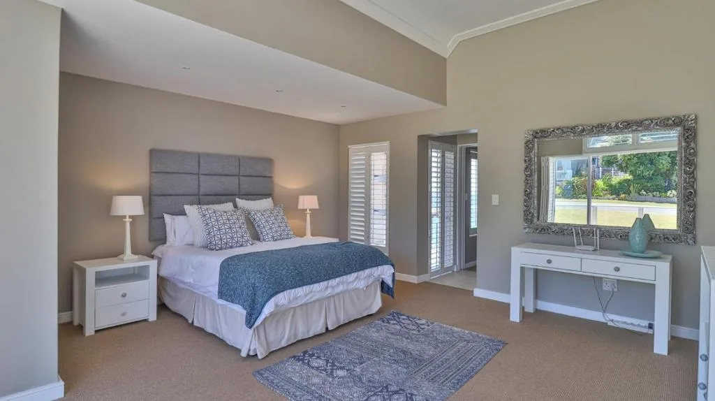 Spacious master bedroom with gray upholstered headboard and garden views