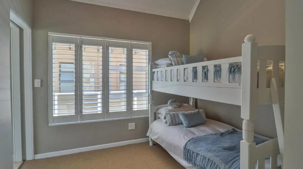 Bright bedroom with white bunk beds and louvered window shutters