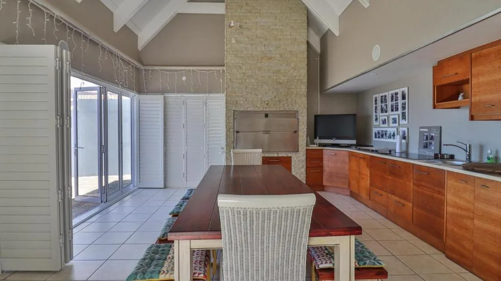 Spacious dining area with wooden table and wicker chairs overlooking kitchen