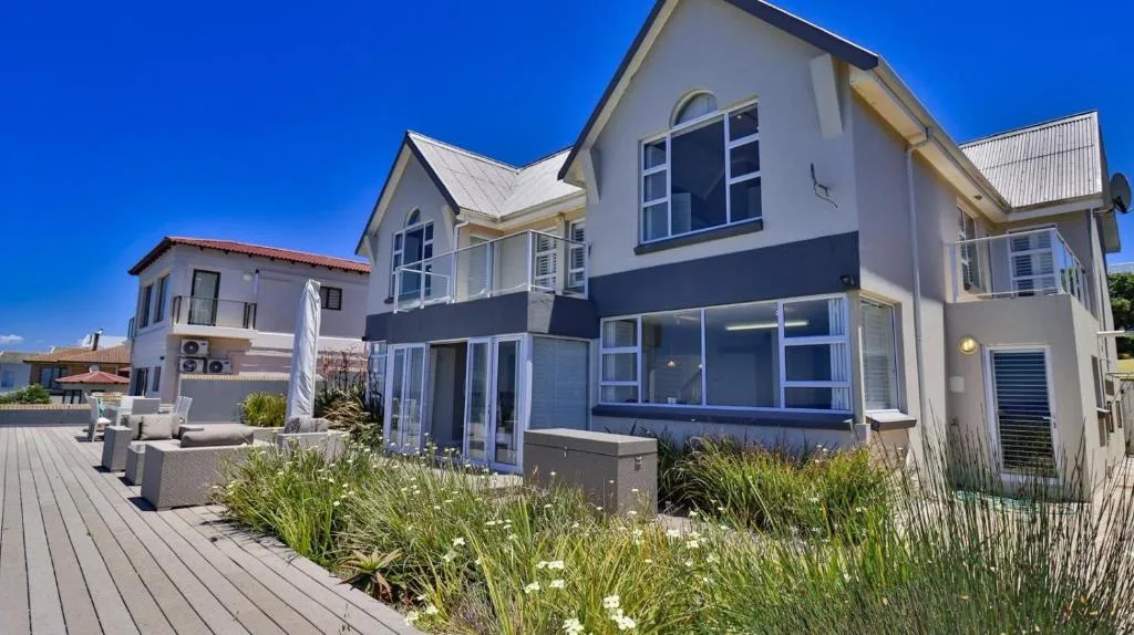 Modern white and blue house with large windows and wooden deck garden