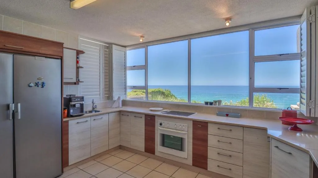 Modern kitchen with ocean view through large windows overlooking the coast
