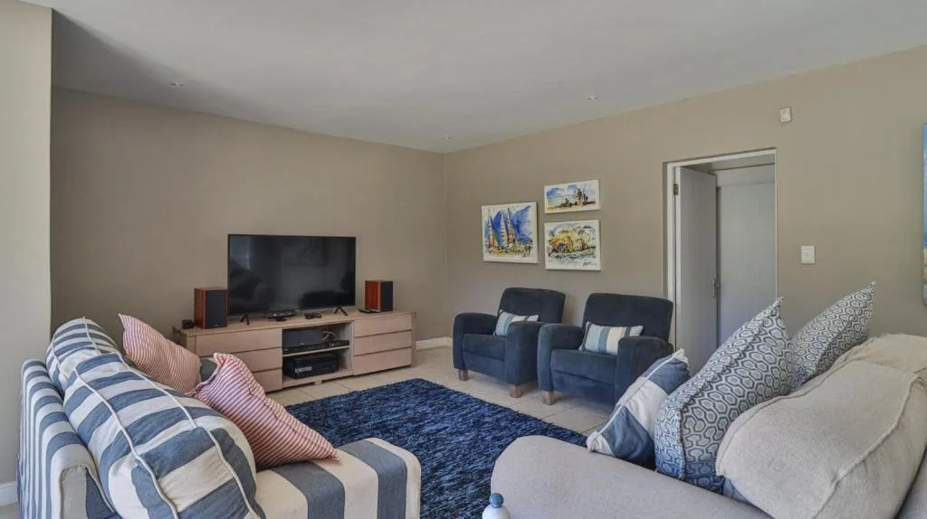 Spacious lounge with striped sofas, TV console, and blue armchairs