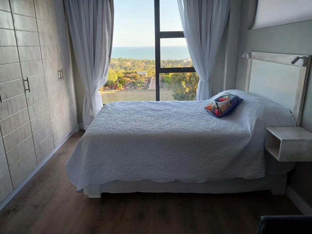 Bedroom with ocean and lagoon views through large windows, white bedding