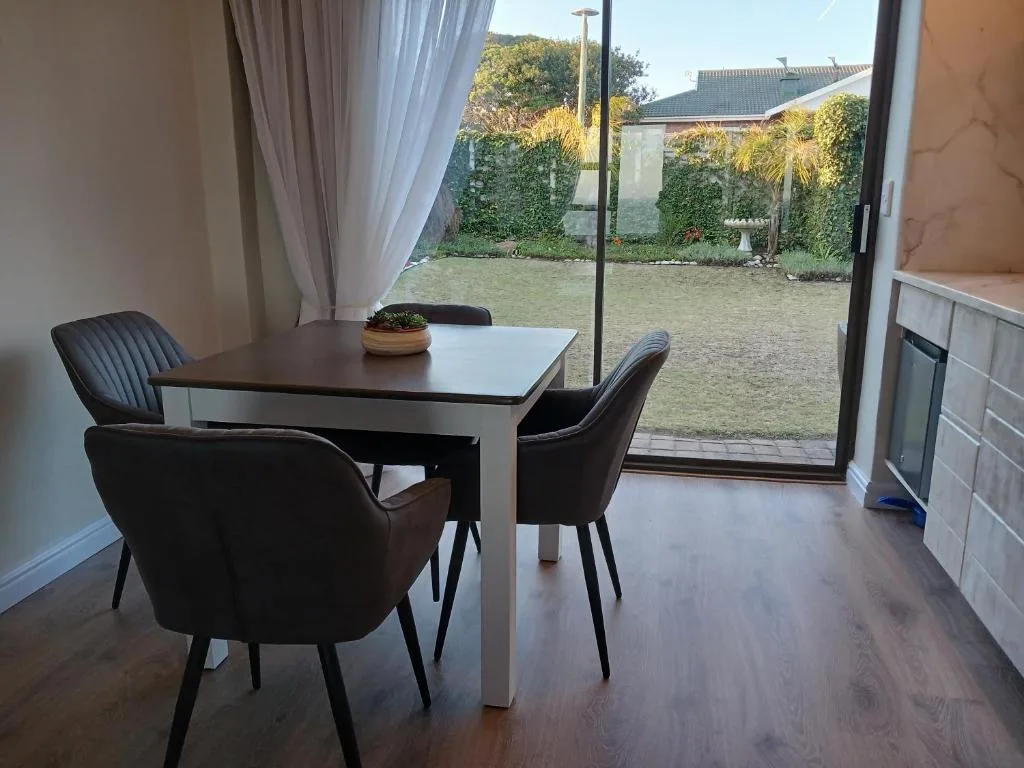 Modern dining table with black chairs overlooking garden courtyard