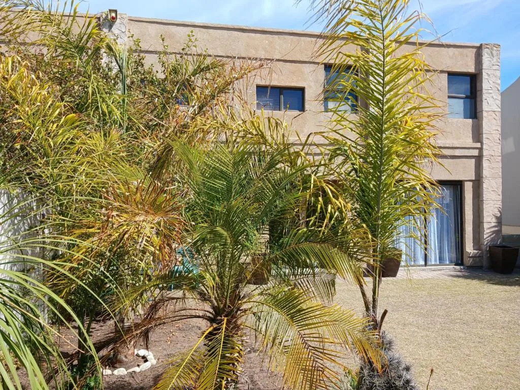 Modern stone building with palm trees and coastal gardens in morning light