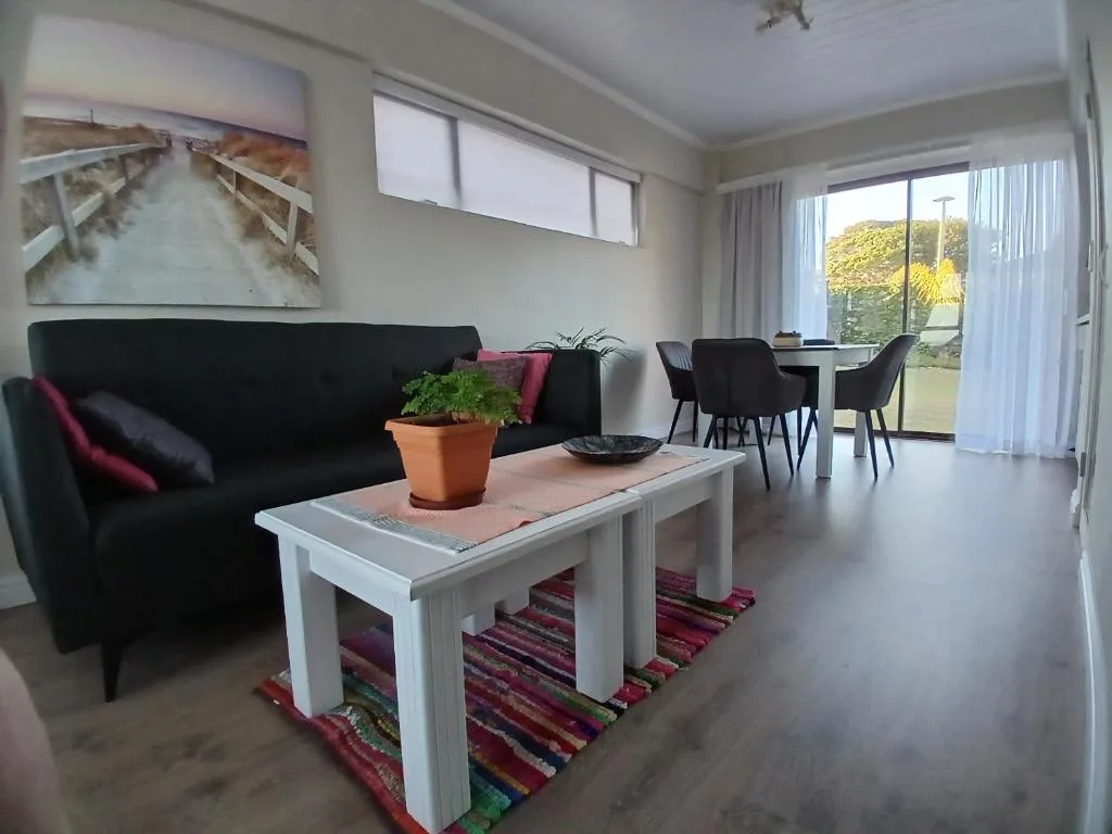 Modern living room with black sofa, white coffee table, and dining area beyond