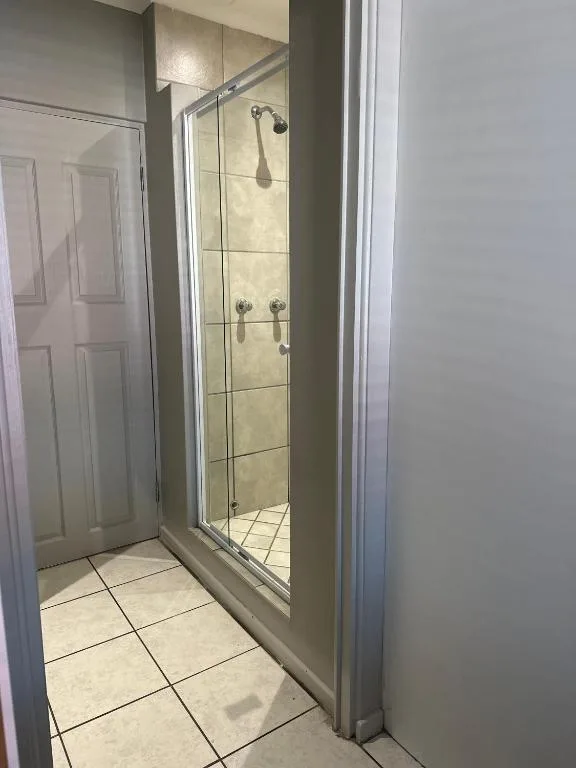 Modern glass-enclosed shower with dual showerheads and tile surround