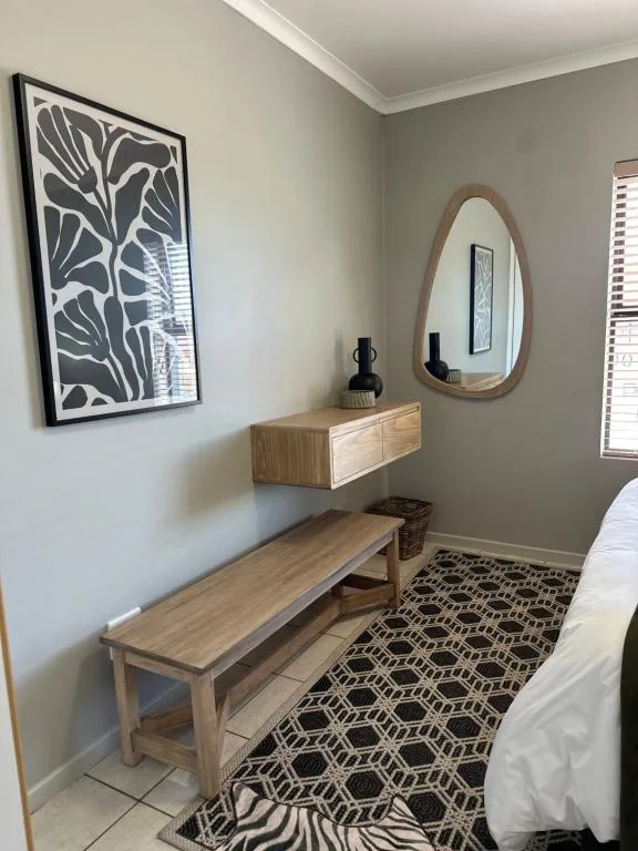 Modern bedroom corner with wooden vanity, mirror, and decorative wall art