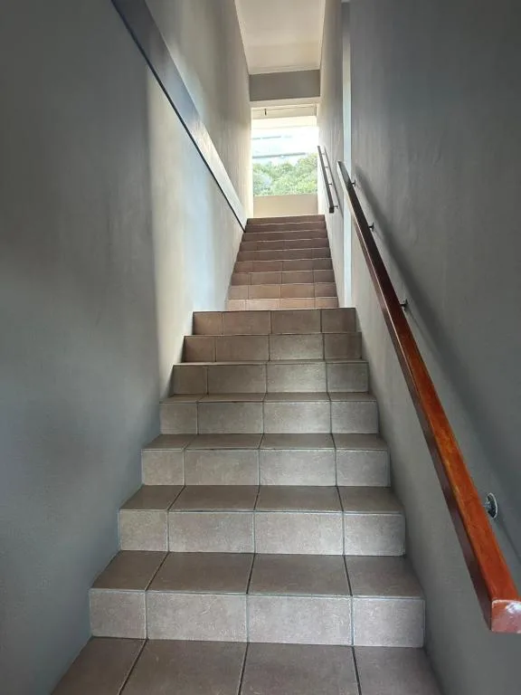 Interior staircase with tiled steps leading upward toward natural light
